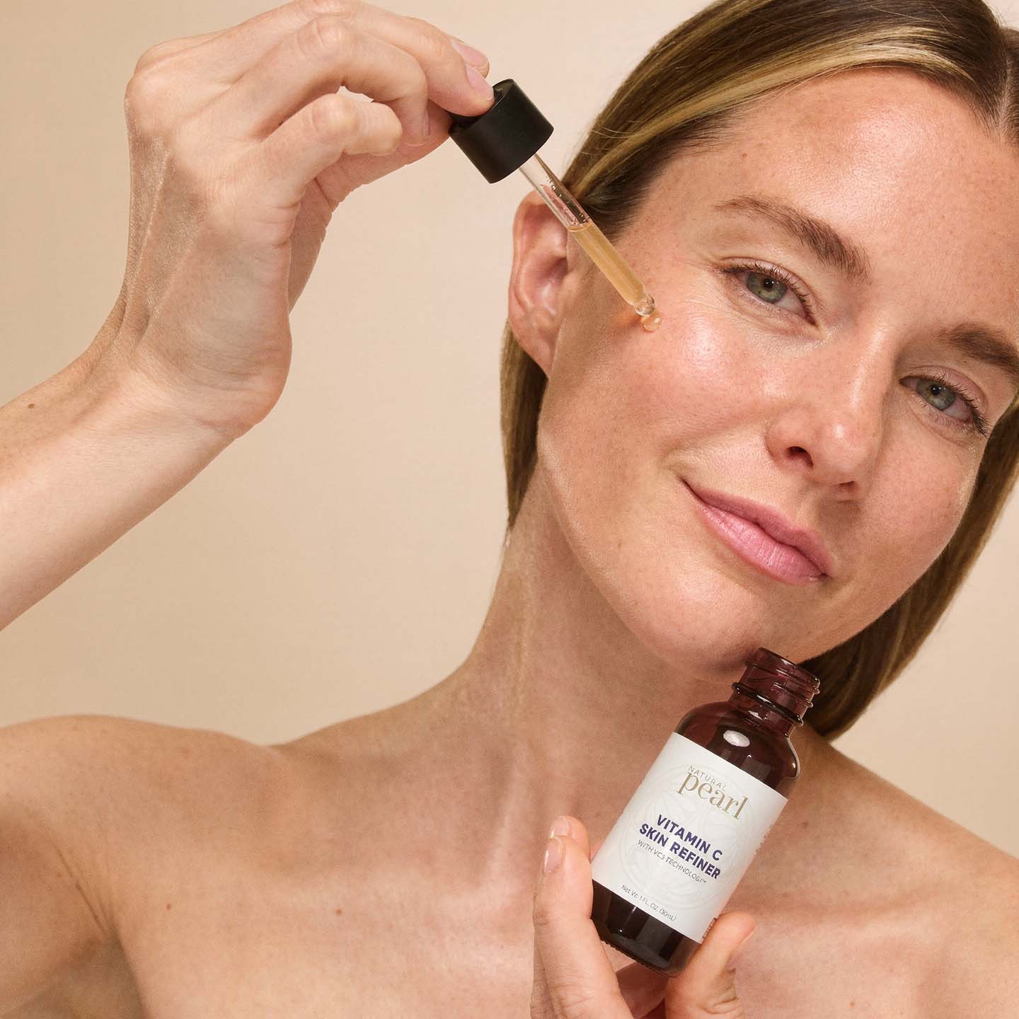 Woman applying Vitamin C Skin Refiner